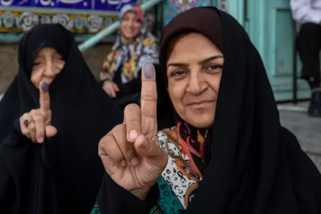 Una mujer iraní muestra su dedo manchado de tinta después de emitir su voto en un colegio electoral.