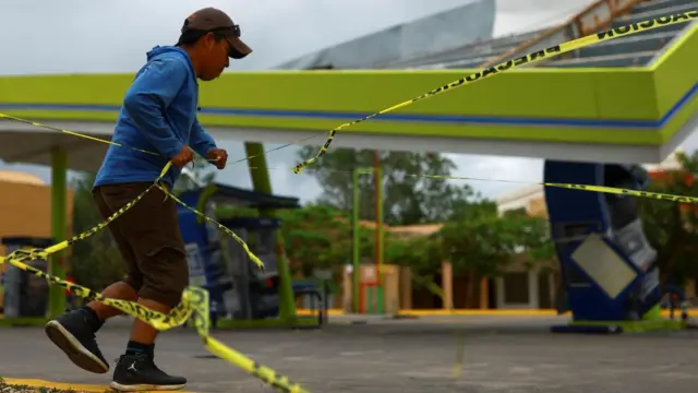 Un hombre pasa por una gasolinera derruida.