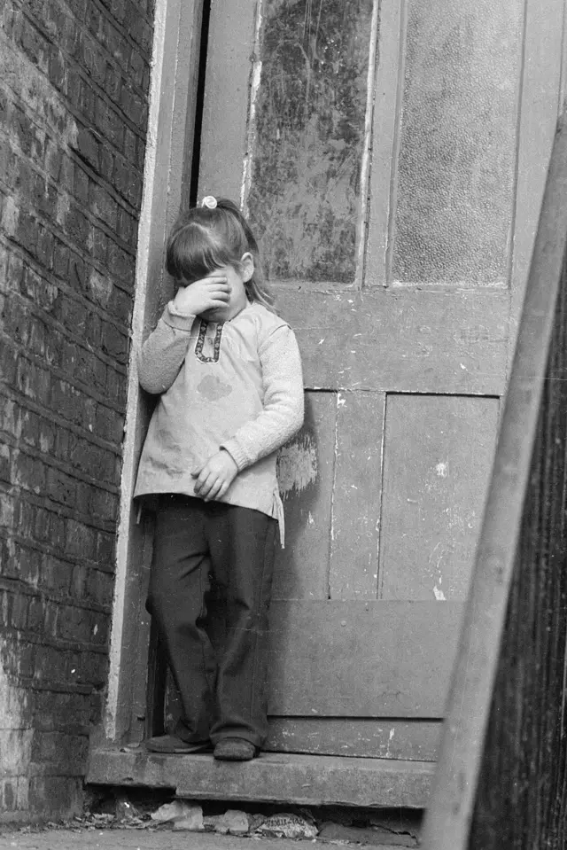 Niña llorando en la puerta de uno de los hogares.