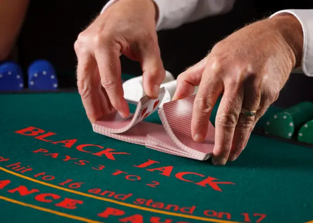 Una persona repartiendo barajas en una mesa de Black Jack