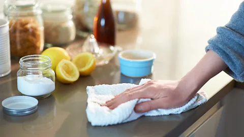 Hand wipes countertop with a white cloth (Credit: Getty Images)