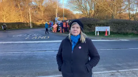 Luke Deal/BBC Alison Downes with Sizewell protesters gathered in the background