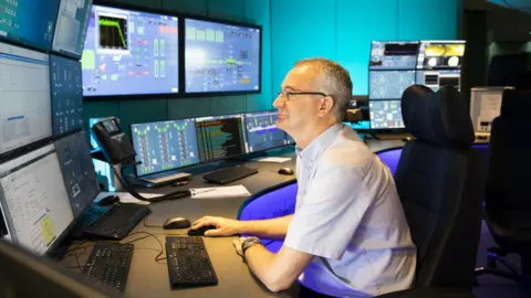 Drax Operator sits in front of dozens of screens