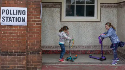 Getty Images Children on scooters outside polling station