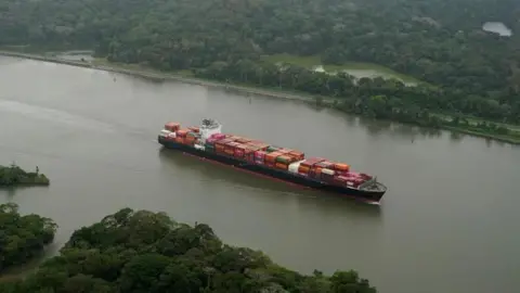 A shipping vessel floats along the Panama canal.