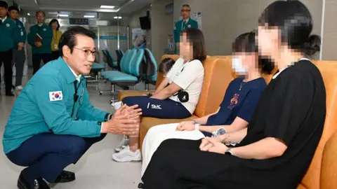 Namwon City Mayor Choi Kyung-sik speaks to patients infected with norovirus in a hospital waiting room.