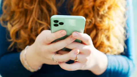 Getty Images A woman's hands holding a mobile phone