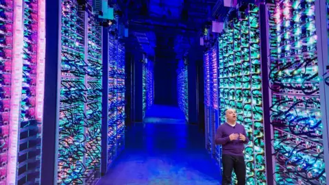 Getty Images A man standing in a data centre with rows and rows of stacked server machines stretching into the distance