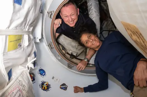 American astronauts Barry Wilmore and Sunita Williams posing for a portrait inside the vestibule between the forward port on the International Space Station