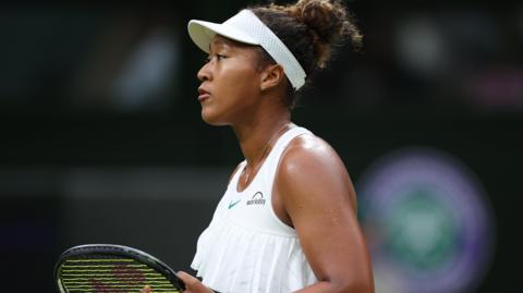 Naomi Osaka holds her racquet during her Wimbledon second-round defeat by Emma Navarro