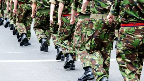 People dressed in camouflage military uniforms marching in a lines