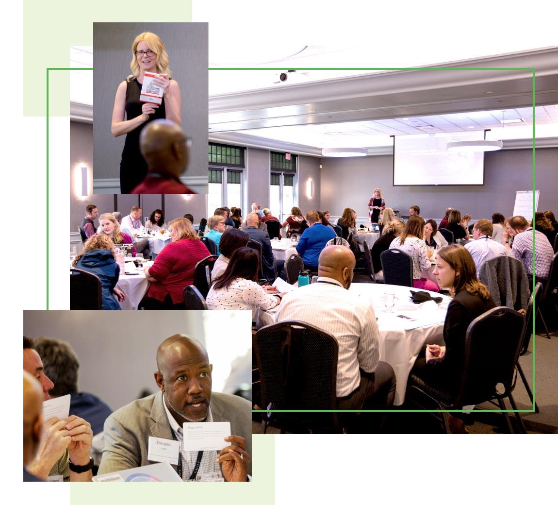 Participants sitting around tables during a Gallup course with one woman raising her hand.