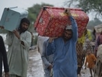 Displaced people carry belongings after they salvaged usable items from their flood-hit home as they wade through a flooded area in Jaffarabad district of Pakistan.(AP)