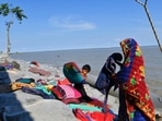 A Bangladeshi woman and a child try to salvage their belongings after tropical storm Sitrang lashed the Bay of Bengal coast on Tuesday in Bhola district, Bangladesh. (AP)