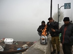 People keep themselves warm on a cold and foggy morning at Dal Lake in Srinagar. Night temperatures across Kashmir dropped below the freezing point.(HT Photo/Waseem Andrabi)