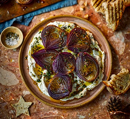 Baked red onions with ricotta on terracotta plate