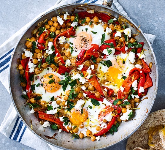 Chickpea, red pepper, egg & feta hash served in a large silver pan resting on top of a tea towel