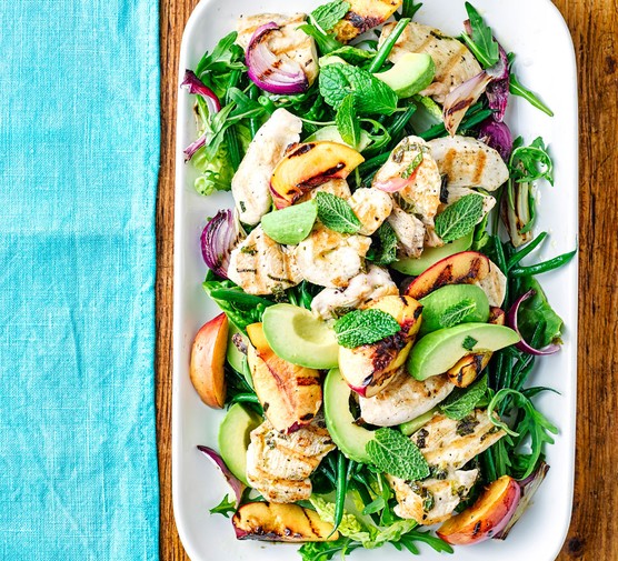 Platter of chicken, peach, avocado and leaves