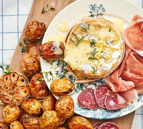 Baked camembert on a plate with sliced meats jersey royal potatoes