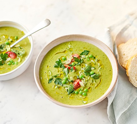 Easy green gazpacho in two white bowls with fresh tomatoes