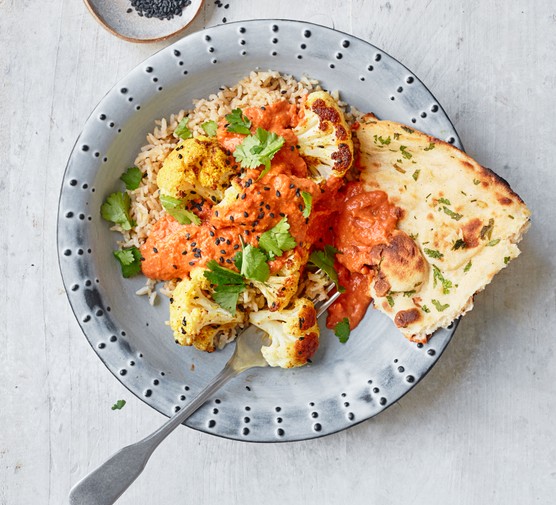 Roasted cauliflower and cashew curry on a plate with rice and naan