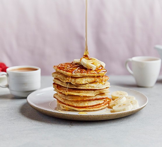 A stack of pancakes topped with bananas and syrup