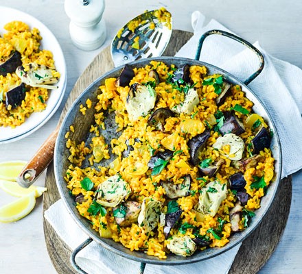 Artichoke and aubergine rice in a bowl with a serving spoon