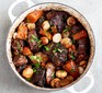 Beef bourguignon in white pot on grey backdrop
