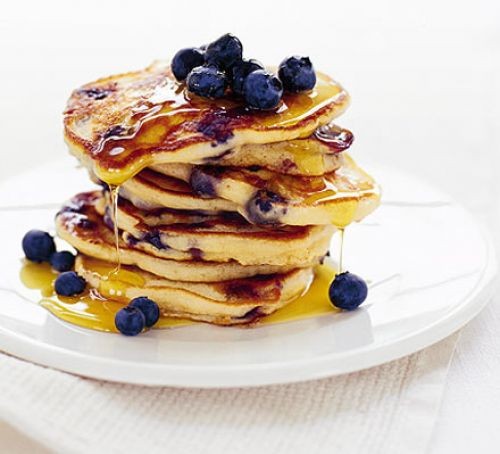 Stack of American pancakes with blueberries and maple syrup drizzle