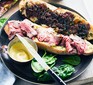 open roast beef sandwich on black plate with knife