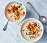 Two bowls of cauliflower soup with chorizo and crouton topping