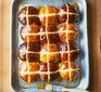 Dark and light hot cross buns on tray with glazing brush