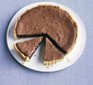 Baked chocolate tart with two slices cut out, on a plate