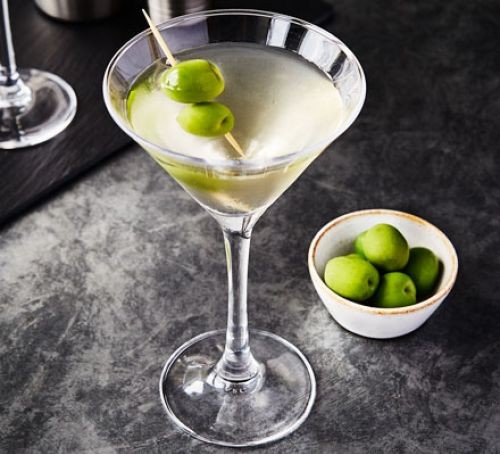 A glass of dirty martini with olives on a cocktail stick