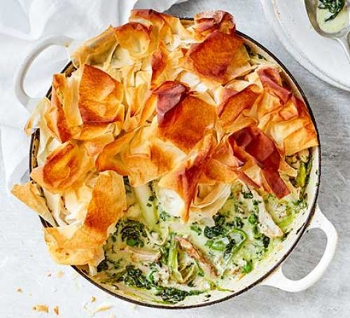 Herby spring chicken pie in a baking dish topped with filo pastry