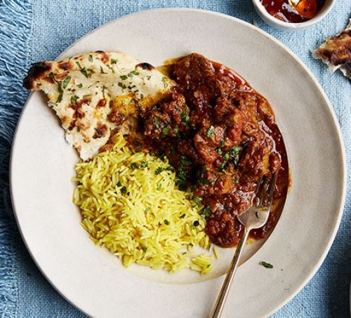 Bowl of lamb curry with flatbread and rice