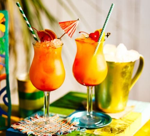 Rum punch in two glasses with cocktail umbrellas and straws