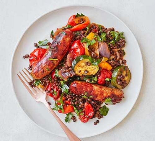 sausages with roasted vegetables and puy lentils on a plate