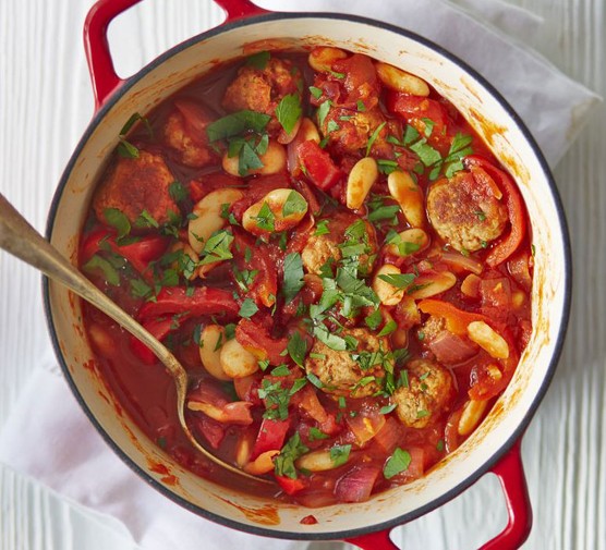Spanish meatball & butter bean stew in a large pot with serving spoon