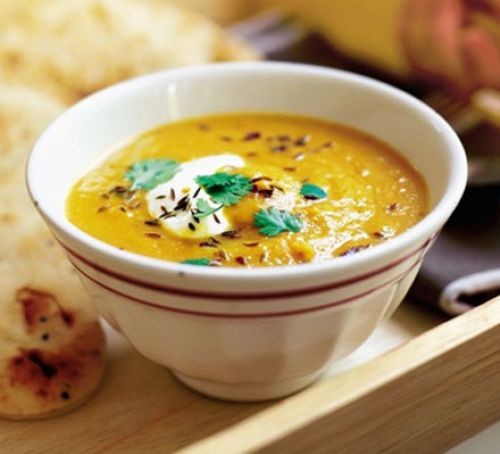 Carrot and lentil soup topped with cumin seeds, yogurt and coriander