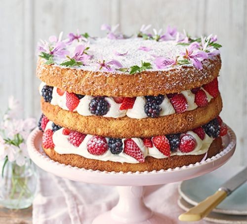 Three-tired sponge cake with berries, icing and flowers