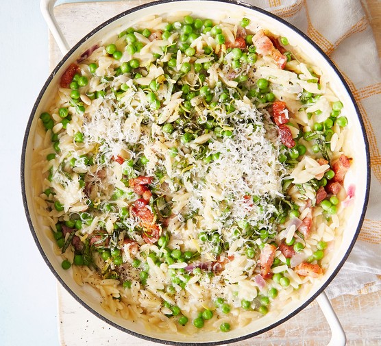 Bowl of pea and pancetta orzotto topped with Parmesan shavings