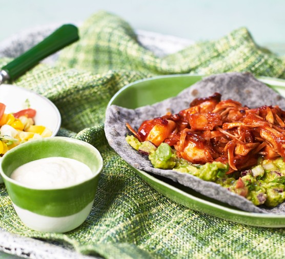 Vegan pulled jackfruit on a plate with guacamole and corn salad