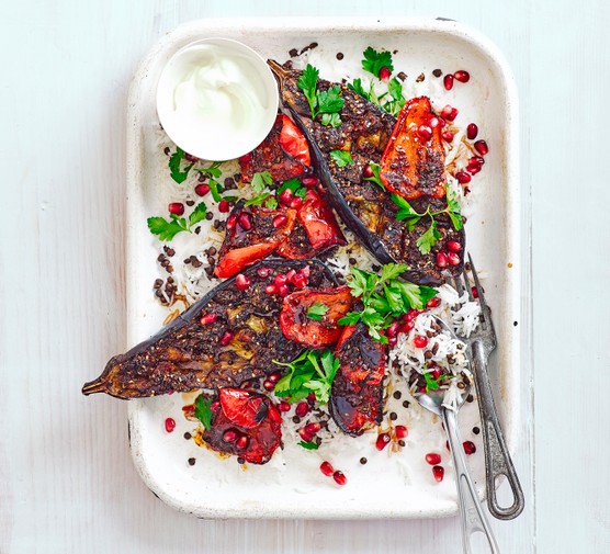 Spice-crusted aubergines and peppers on a tray with rice pilaf and yogurt