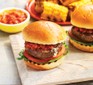 Two barbecue beef burgers on a wooden chopping board