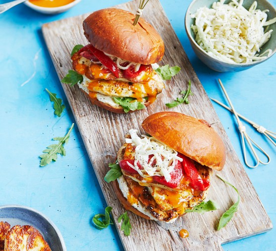 Two chicken and halloumi burgers on a board