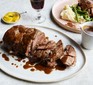 Slow cooker leg of lamb on a platter and plated up in background