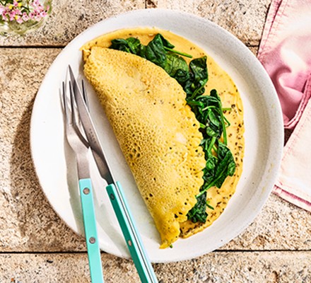 Vegan chickpea flour omelette filled with spinach on a white plate