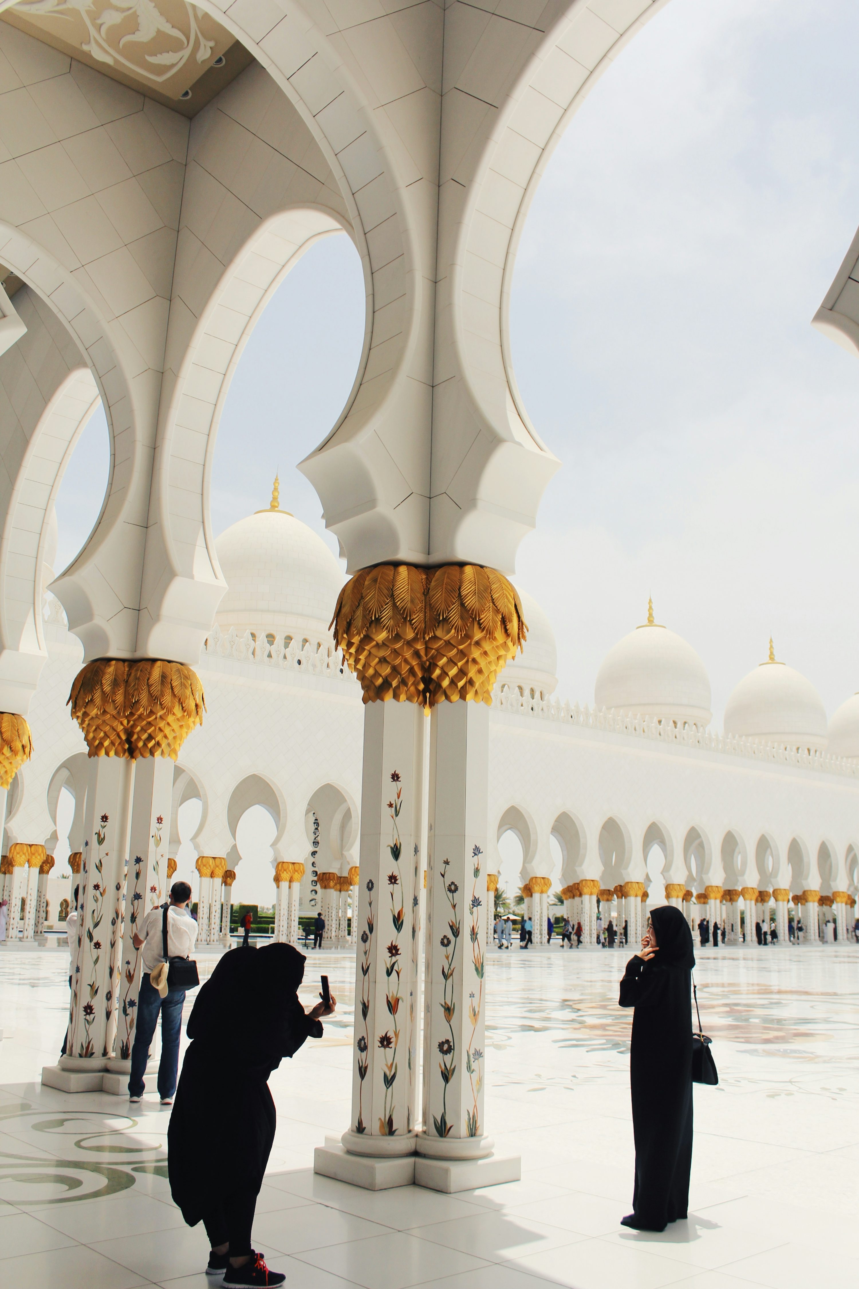 person taking picture of woman wearing abaya and hijab during daytime