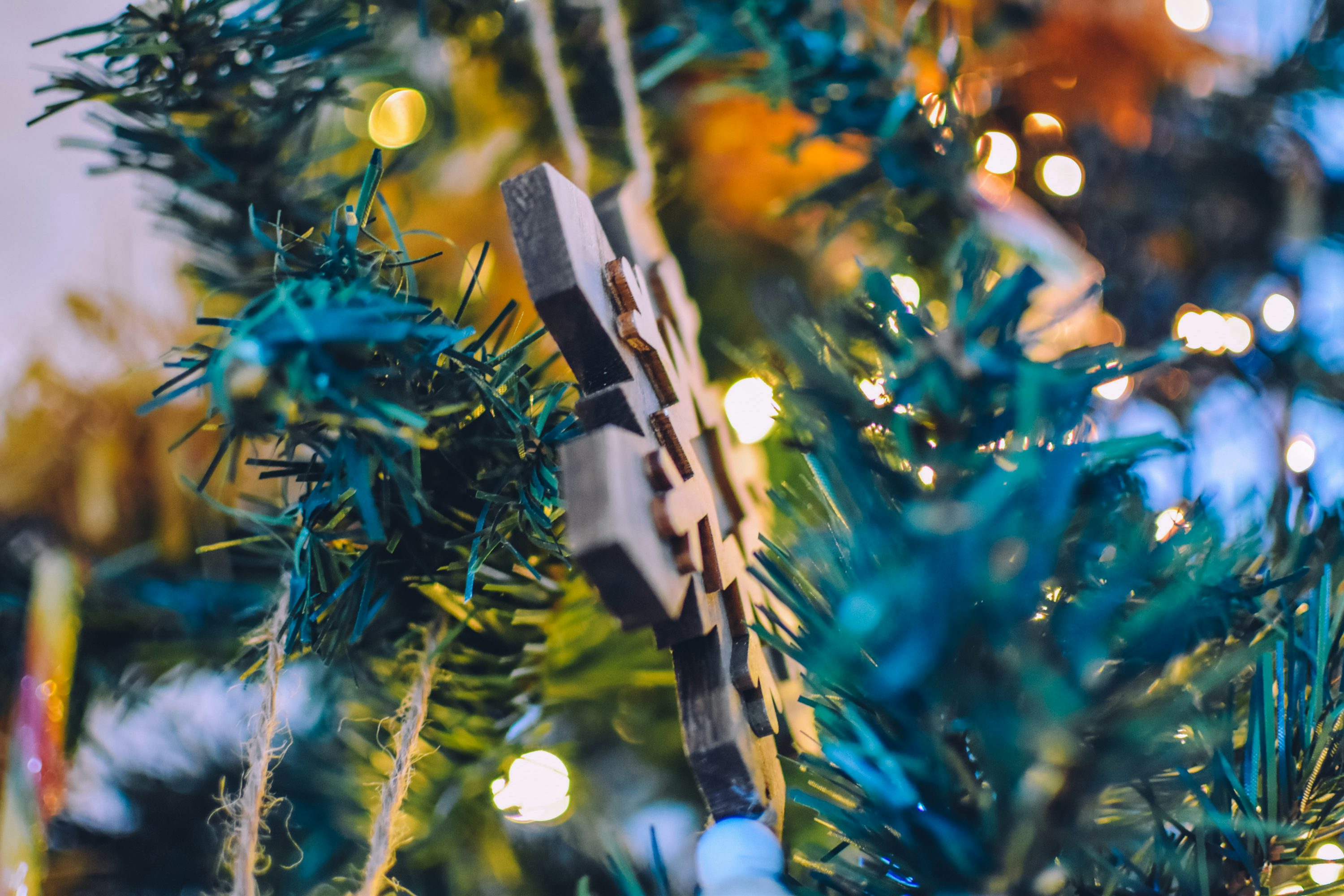 Ornement de croix en bois marron sur arbre de Noël vert